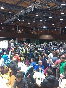 Mehrere hundert Menschen sitzen und stehen in der Halle der Anlaufstelle