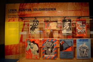 Alles so schön artig hier: Plakate in Kiefernvitrine in der Ausstellung Rock und Pop im Pott