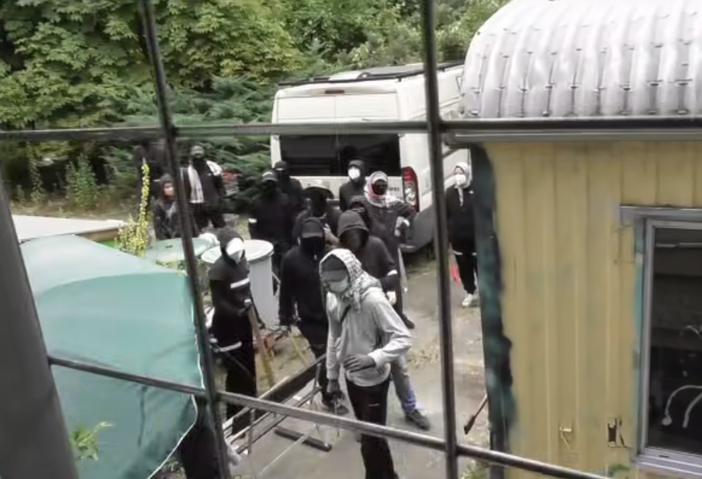 Mit Schlagstöcken und Latten bewaffnete Vermummte vor dem AJZ Kita. Screenshot: Andreas Wolf