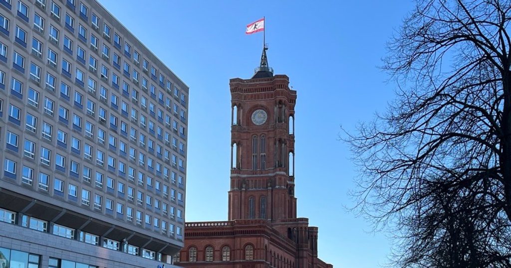 Rotes Rathaus in Berlin im Schnee mit Uhrturm und Berliner Flagge