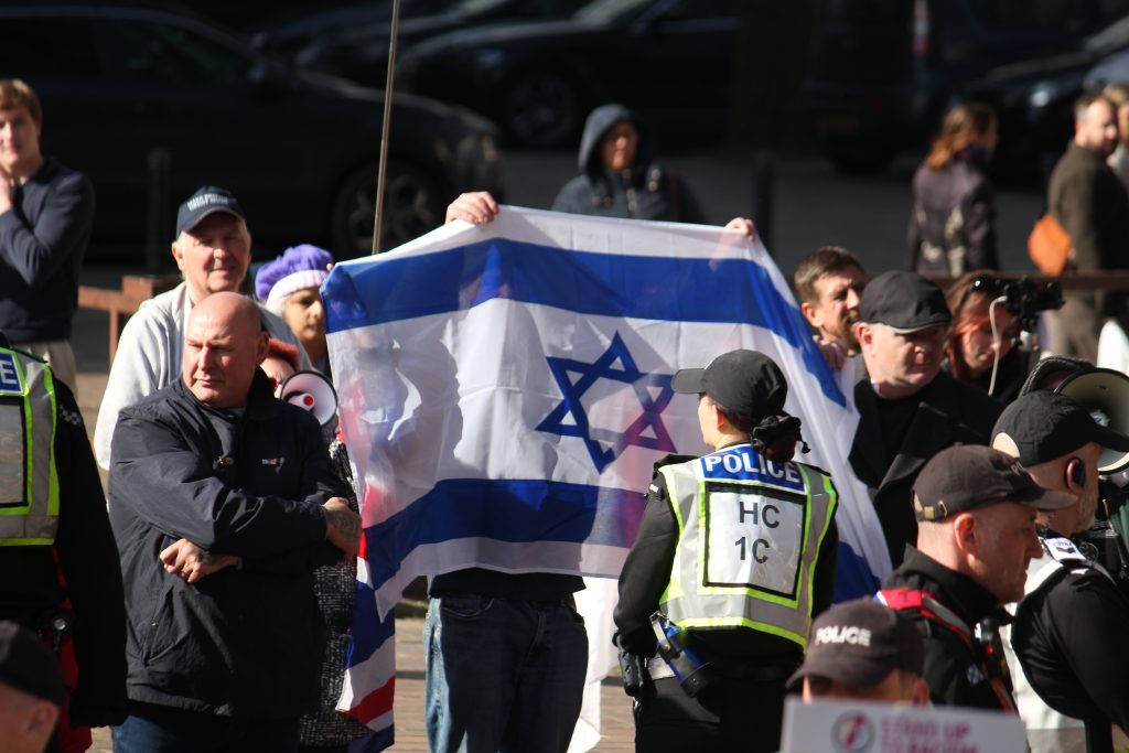 Ein Demonstrant hält eine Israelfahne. Foto: Tim Sheerman-Chase / Wikimedia Commons / CC BY 2.0