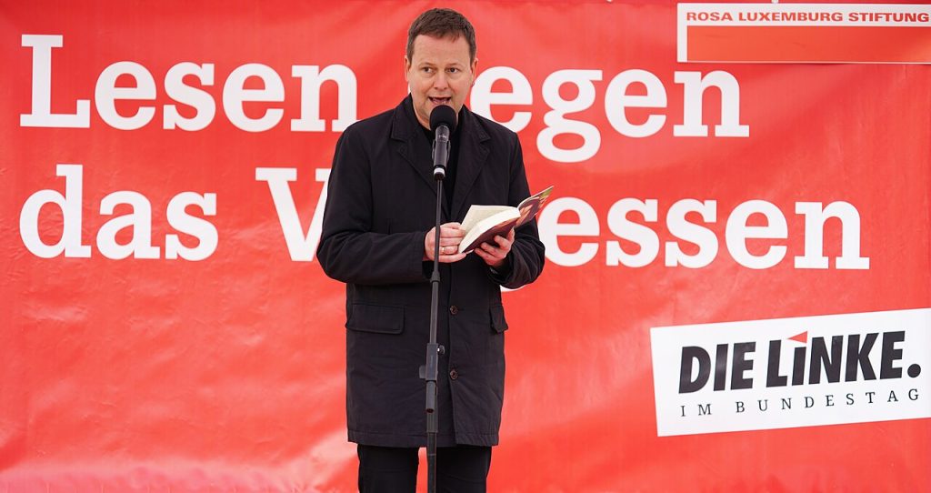 Klaus Lederer liest bei „Lesen gegen das Vergessen“ am 10. Mai 2019 vor rotem Hintergrund.